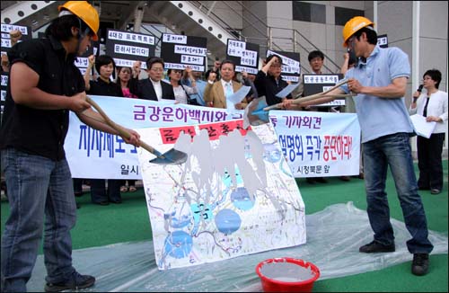 충청지역 시민단체들이 금강운하정비사업 중단을 요구하는 퍼포먼스를 벌이고 있다. 사진은 시민단체 회원들이 금강 지도위에 시멘트를 발라 흉측해지는 모습을 만들어 보이고 있는 장면.